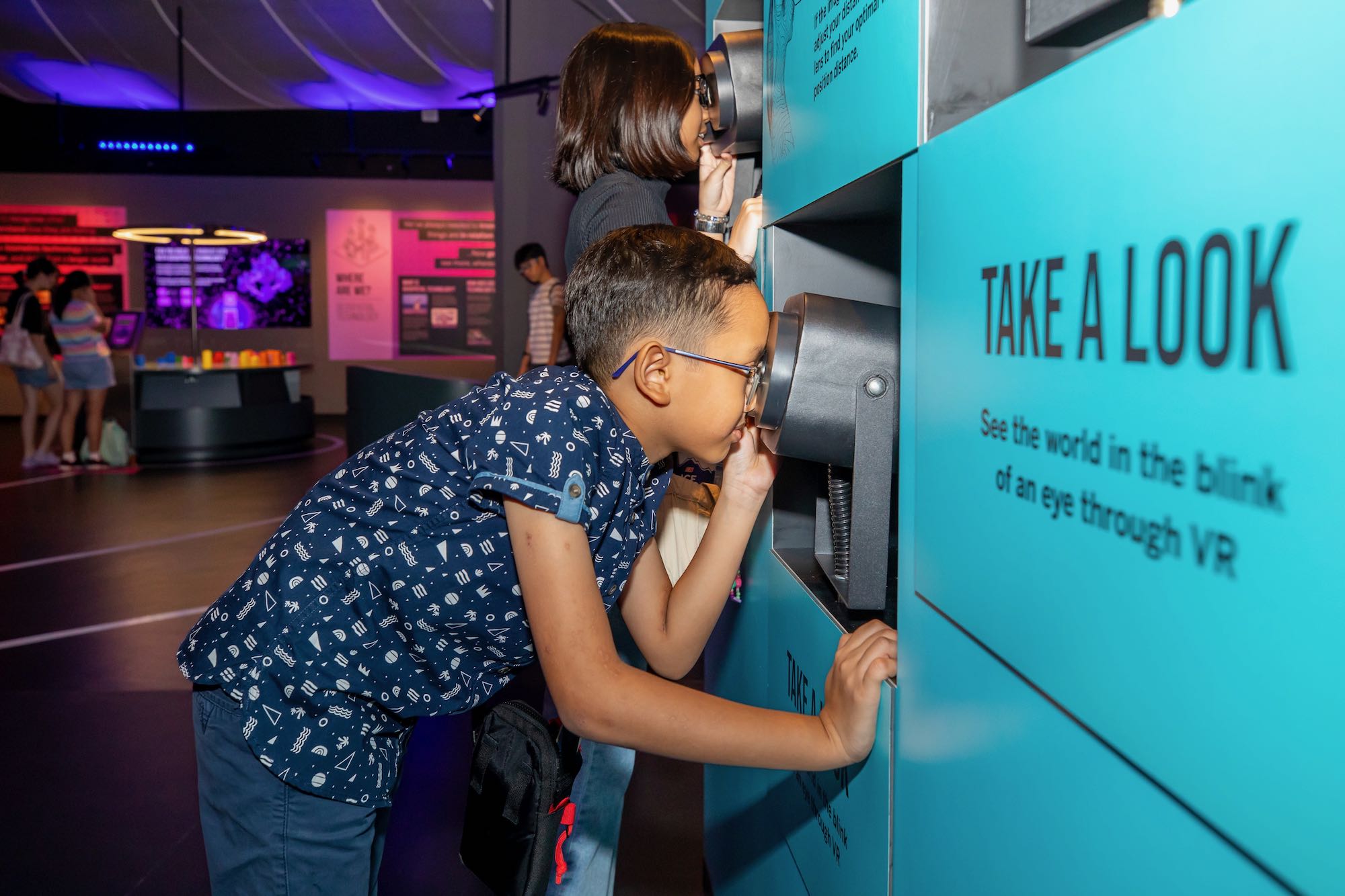 Boy looking into a viewfinder at an exhibition