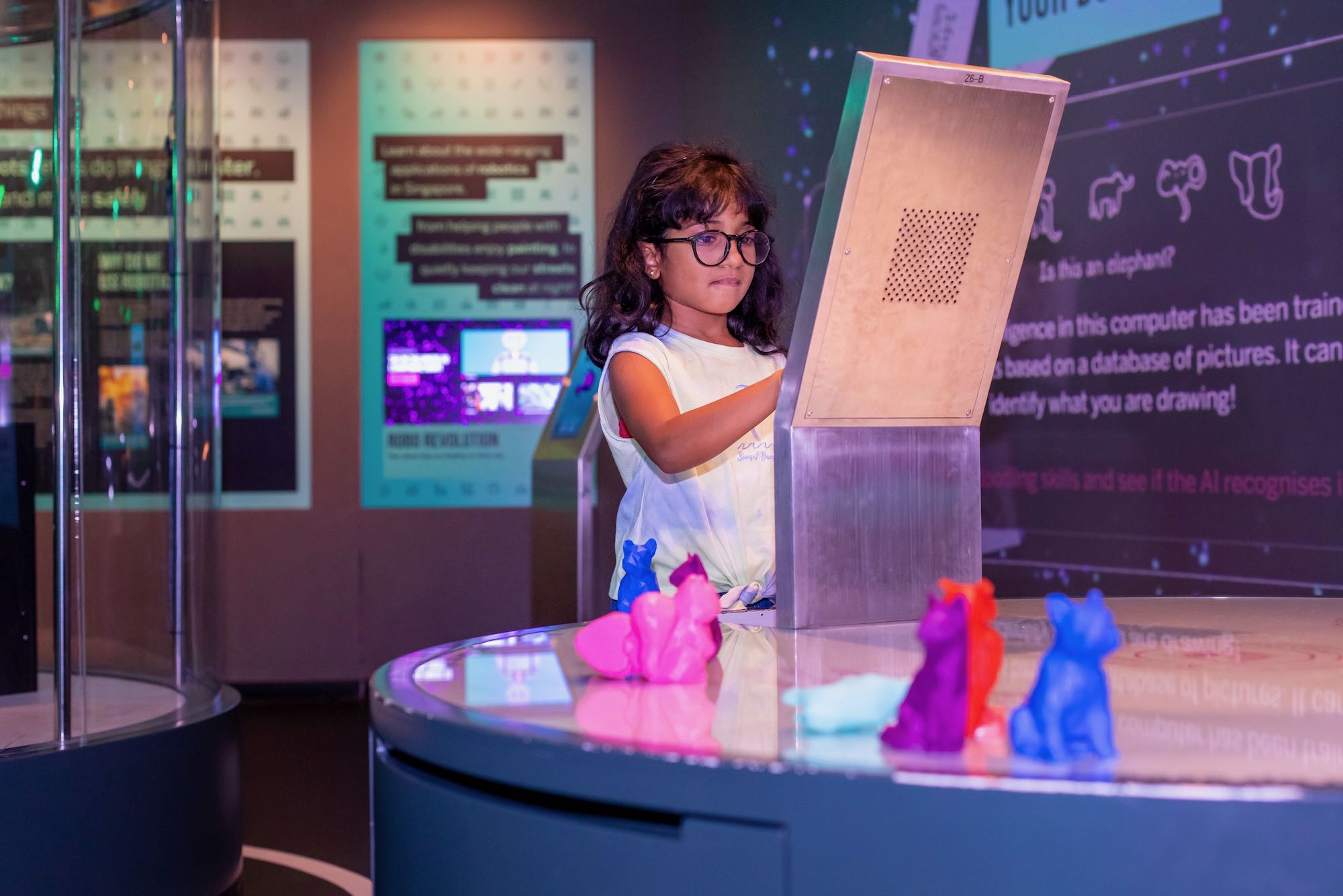 Girl wearing spectacles interacting with a screen at an exhibition